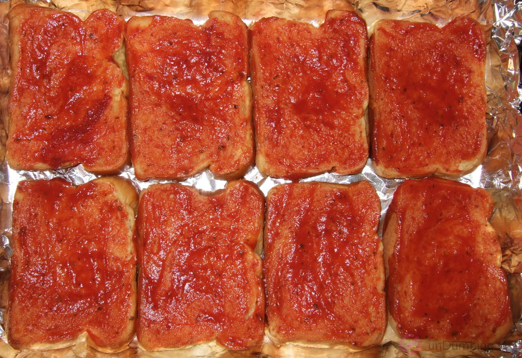 Eight slices of brioche with pizza sauce in a baking pan