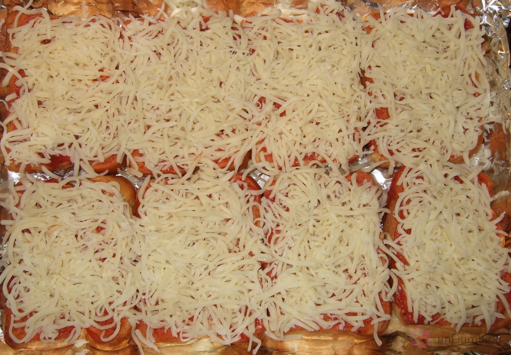 Eight slices of brioche with pizza sauce and shredded mozzarella cheese in a baking pan