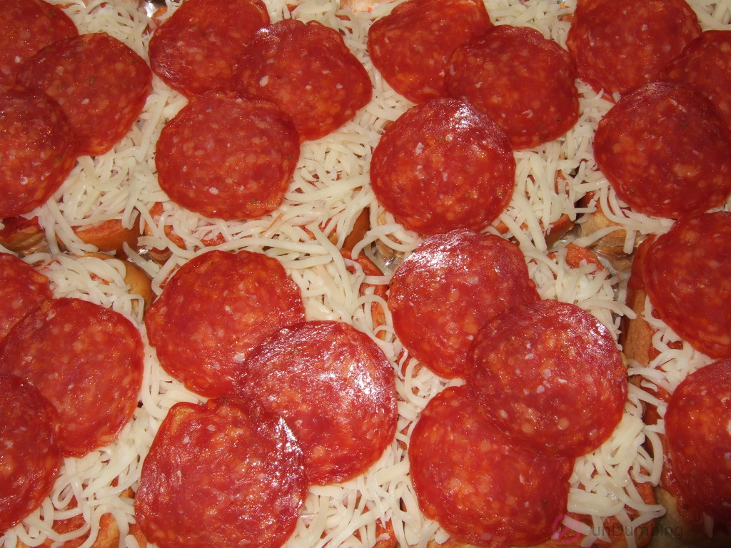 Eight slices of brioche with pizza sauce, shredded mozzarella cheese, and pepperoni slices in a baking pan