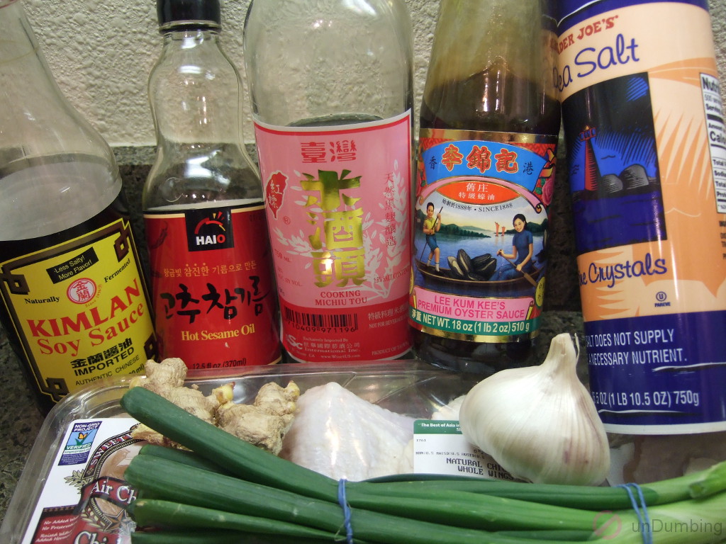 Bottles of soy sauce, hot sesame oil, michiu, oyster sauce, and salt. Ginger, garlic, green onions, and chicken
