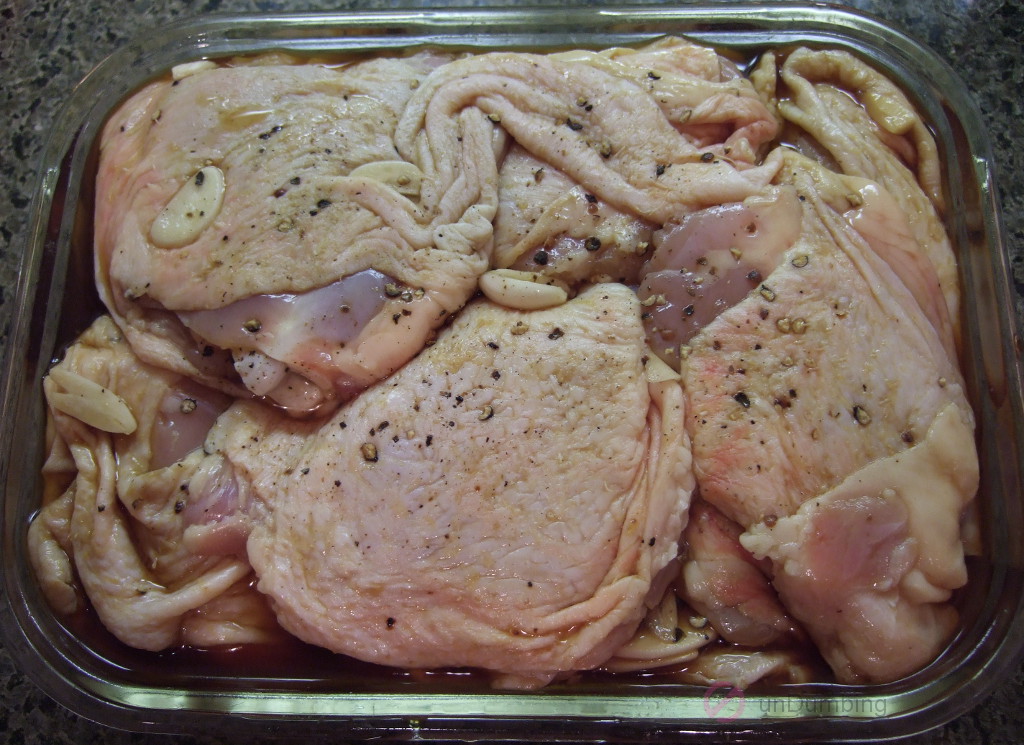 Chicken thighs marinating in glass container