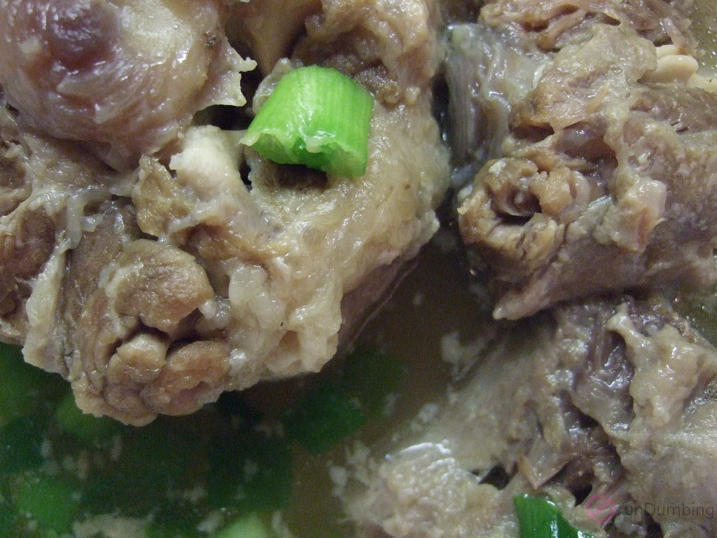 Oxtail soup in a pot with green onions