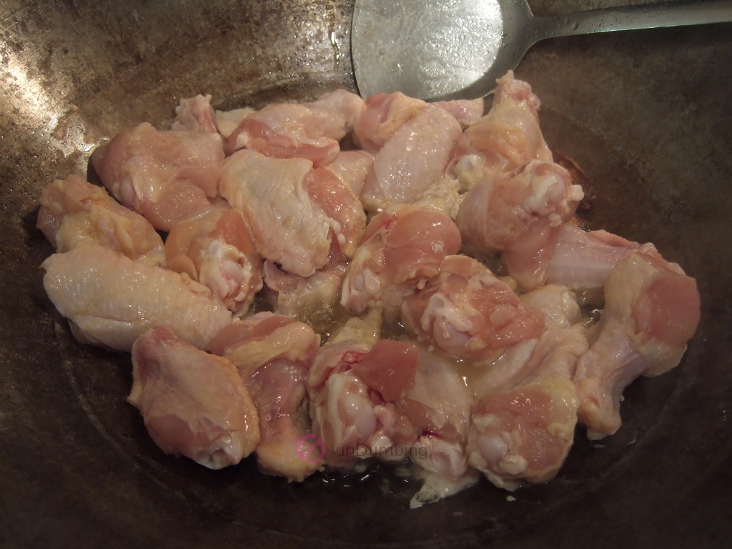 Chicken wings in a wok with oil and ginger