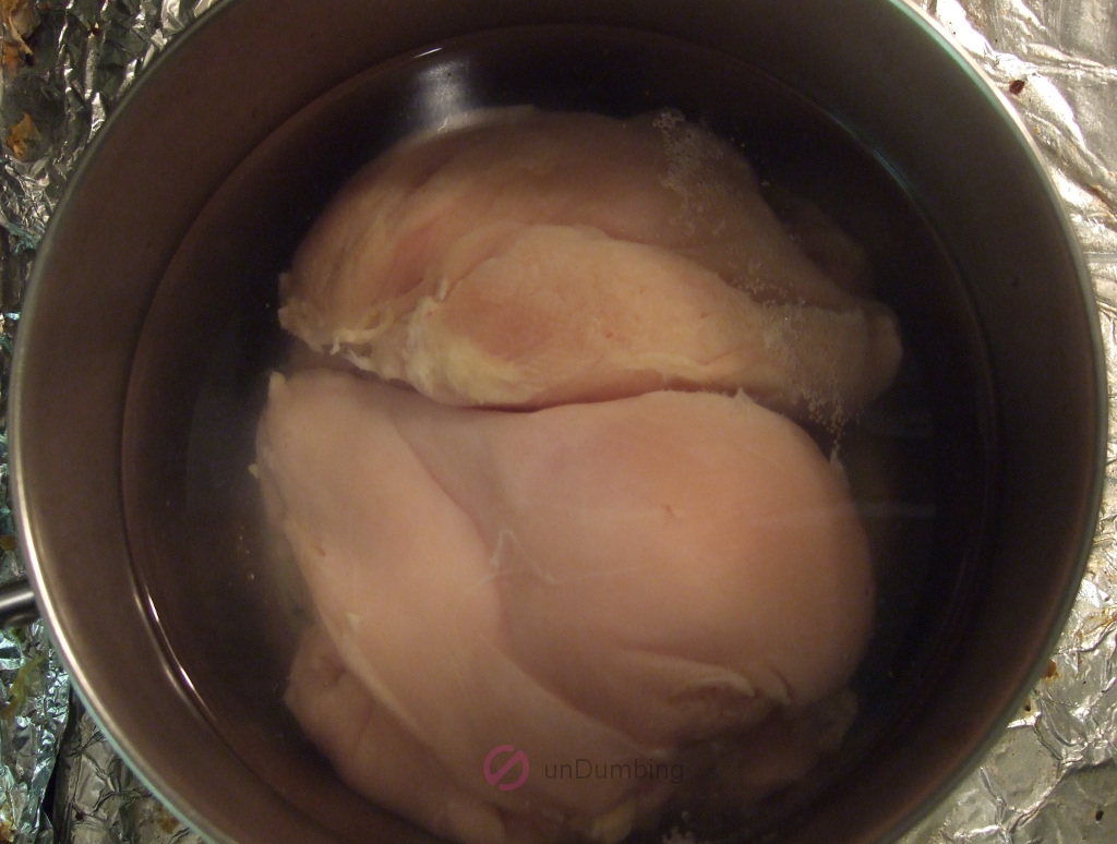 Chicken covered in water in a pot