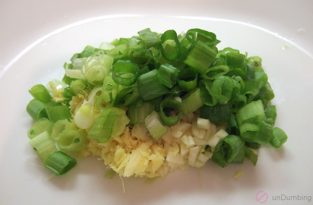Minced ginger, minced garlic, and chopped green onions on a plate