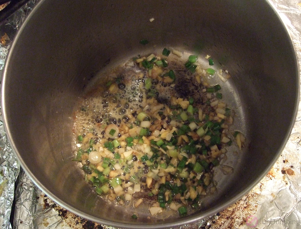 Ginger, green onions, and garlic cooking in saucepan