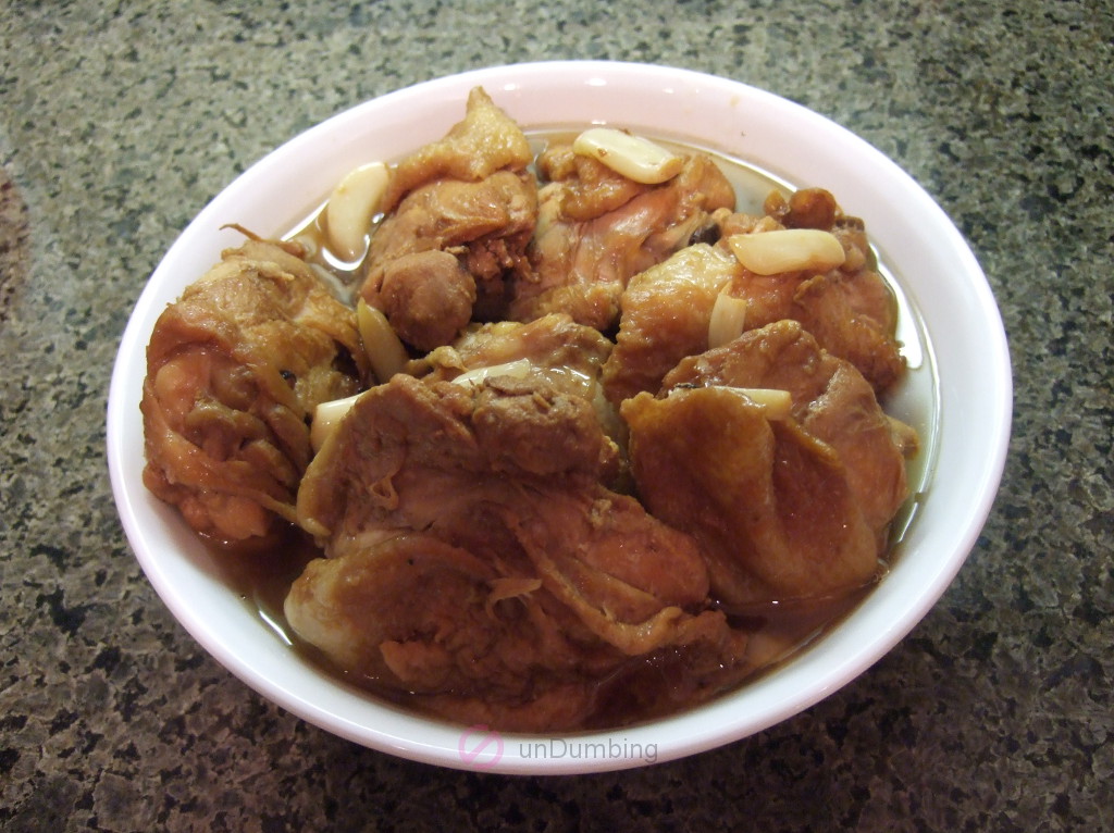 Bowl of chicken adobo garnished with garlic