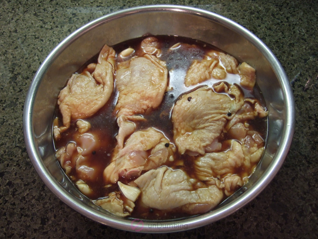 Chicken thighs marinating in a stainless steel bowl
