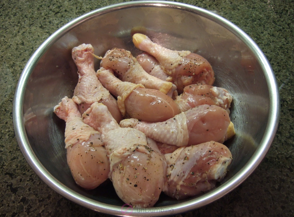 Chicken seasoned with salt and pepper in a stainless bowl