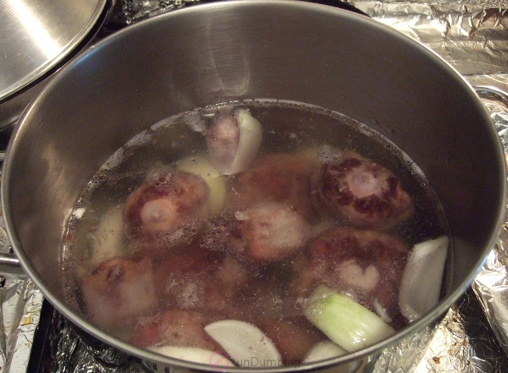 Bringing a pot of water, onions and roasted oxtail to boil
