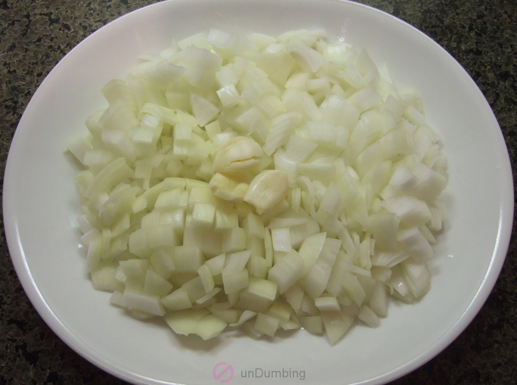 Chopped onions and crushed garlic cloves on a white plate