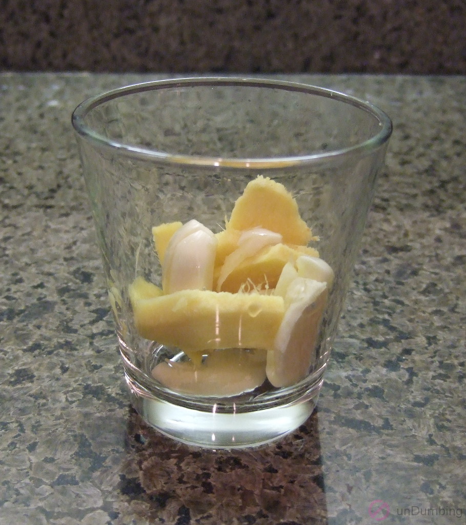 Ginger slices and smashed garlic in a shot glass