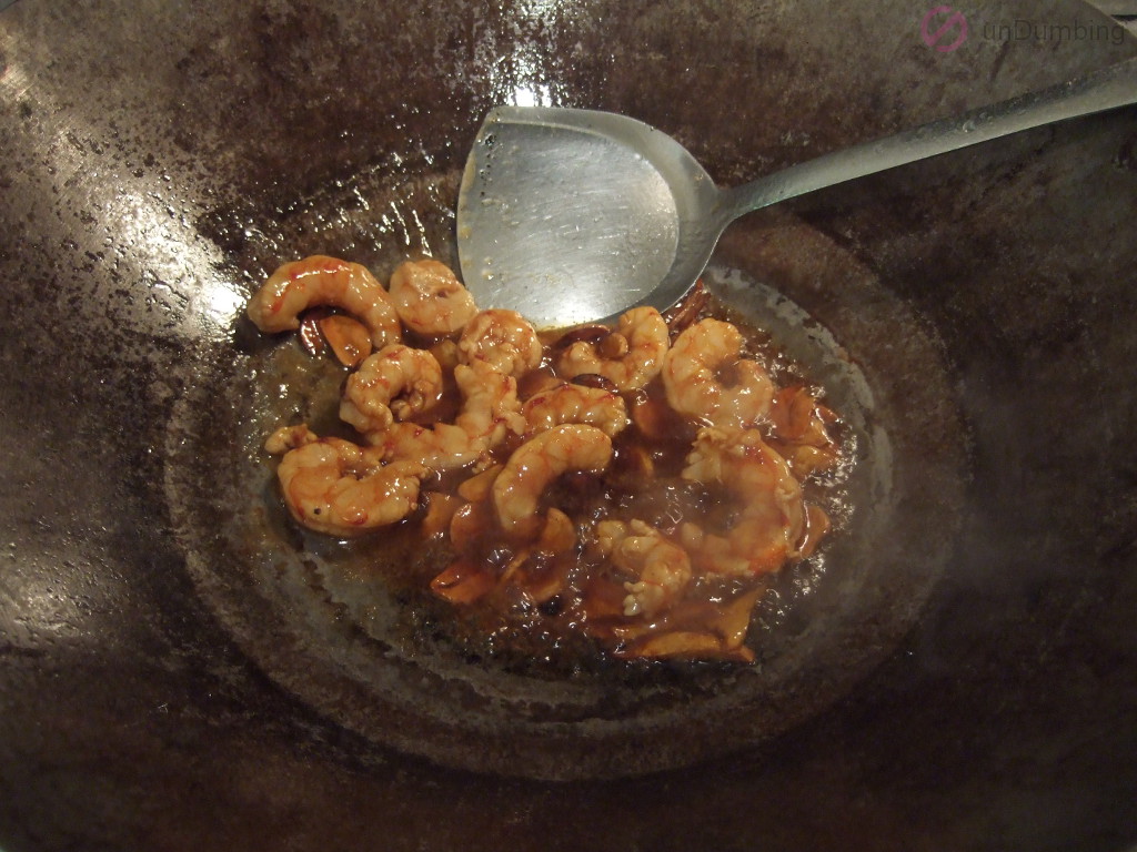Cooking added shrimp and marinade in the wok