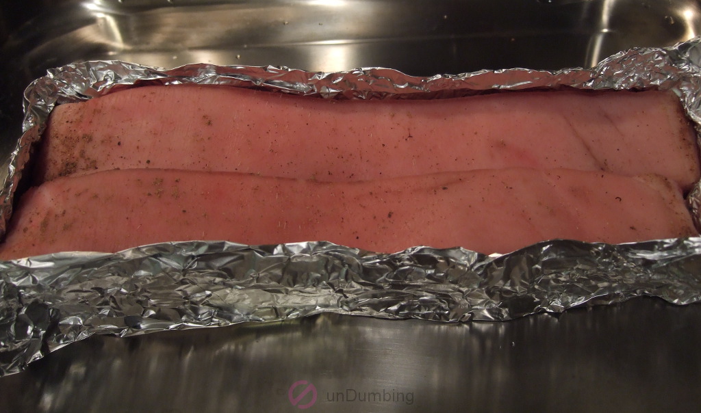 Pork belly contained in foil on a roasting pan