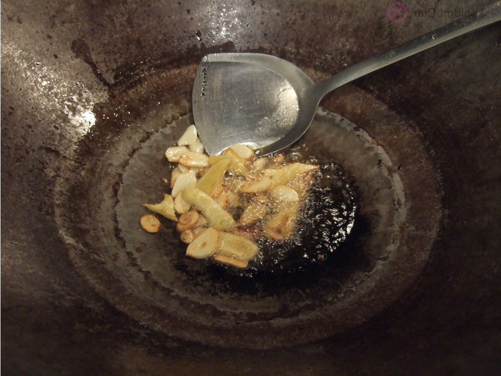 Garlic and ginger cooking in oil in a wok