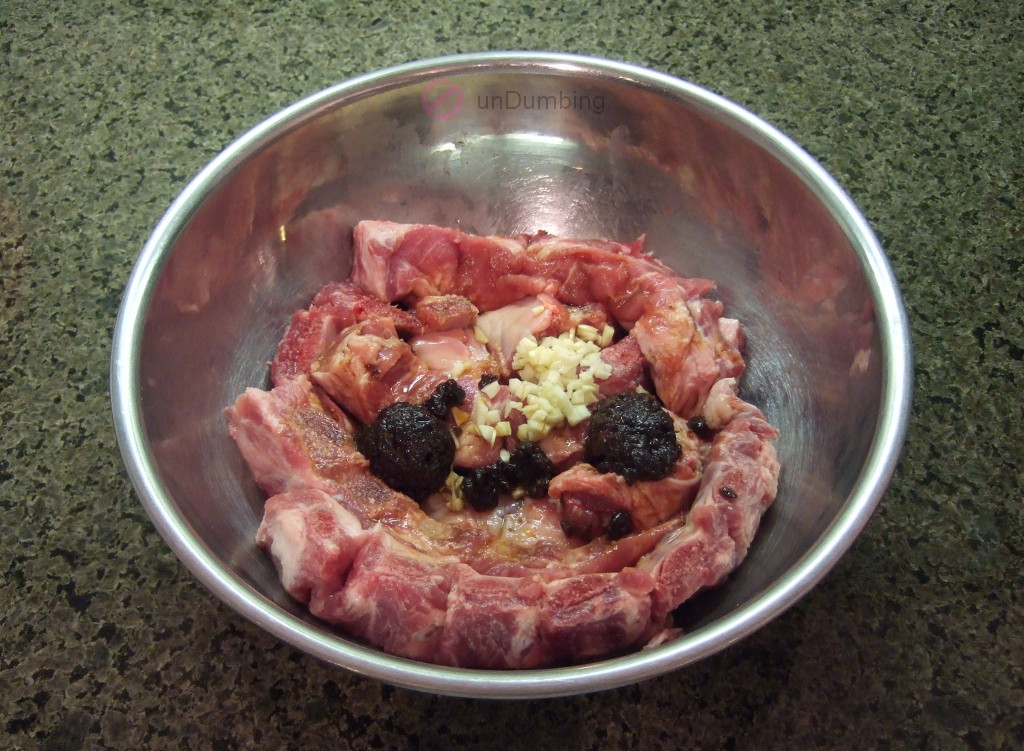 Ribs with marinade ingredients in a metal bowl