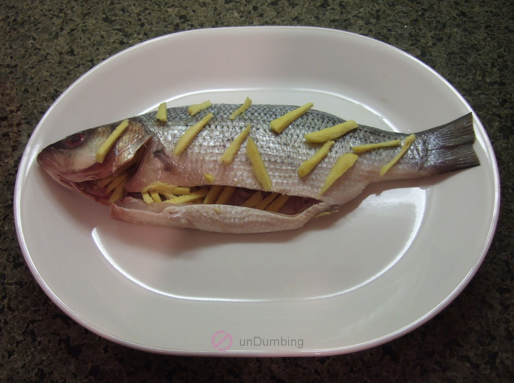Bass with ginger strips on a white plate
