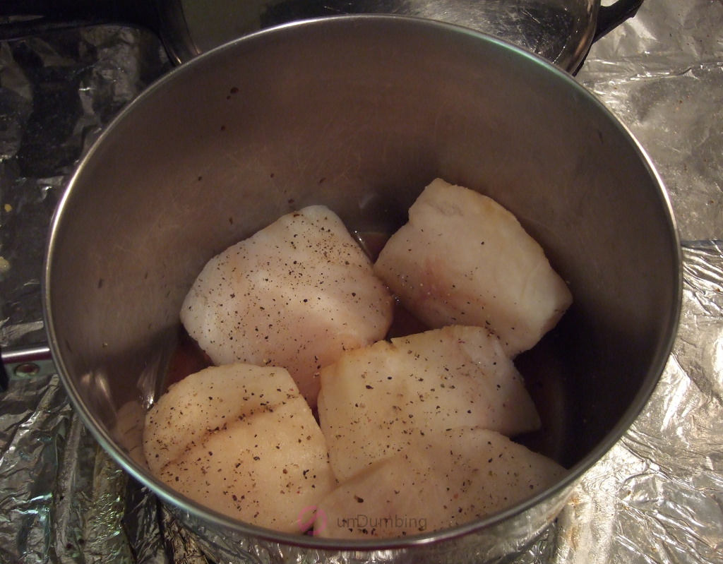 Seasoned cod simmering in a saucepan