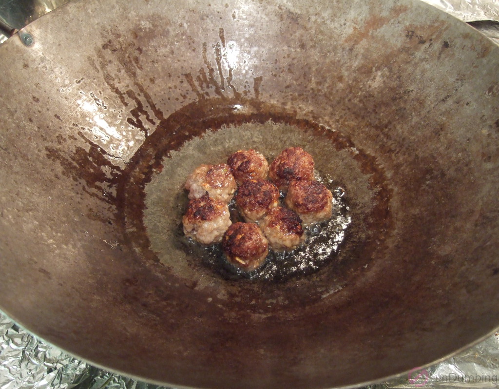 Meatballs in a wok after flipping