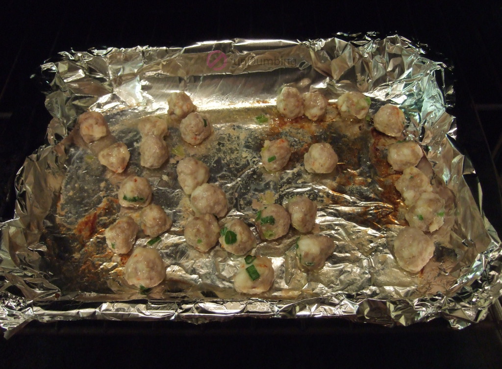 Baked meatballs on a foil-lined baking pan