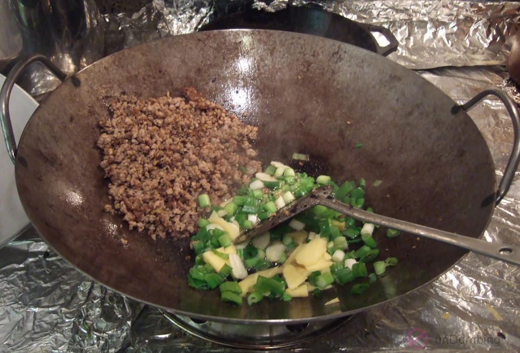 Garlic, ginger, and green onions added to the wok
