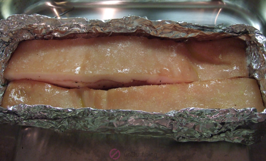 Seasoned pork belly in a foil tray on a roasting pan