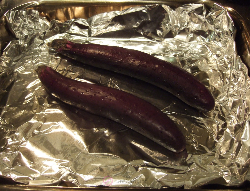 Eggplants with tiny holes on a foil-lined roasting pan