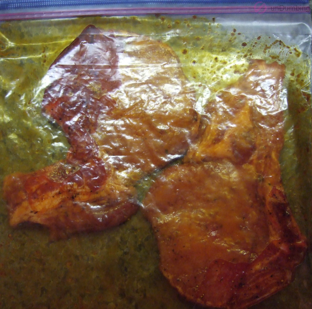 Pork chops rubbed with seasoning in a clear plastic bag