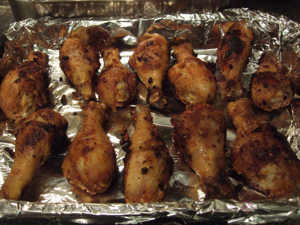 Browned chicken drumsticks in a foil-lined baking pan