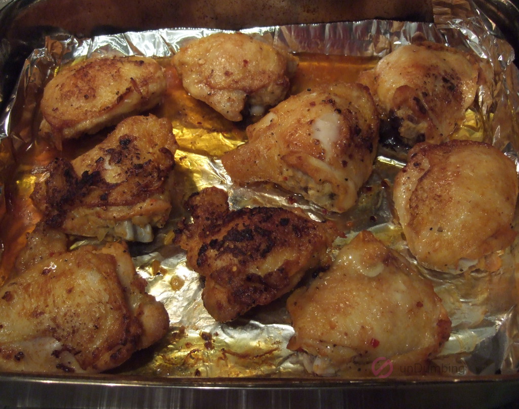 Baked chicken thigs from the oven in a foil-lined roasting pan