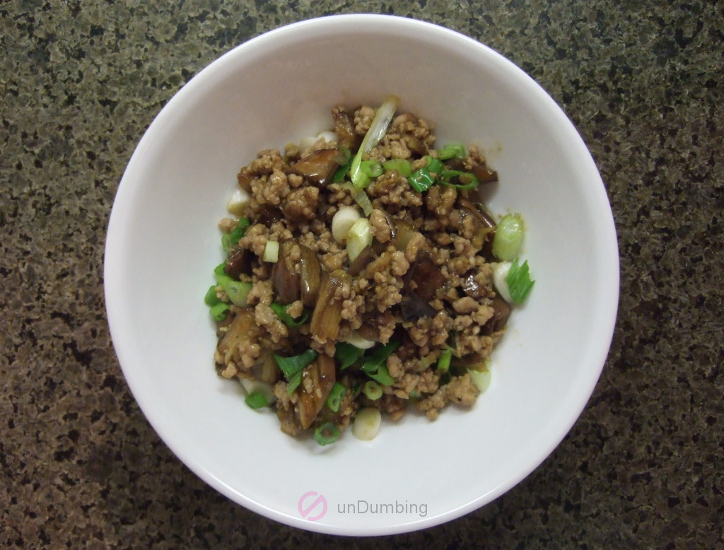 Ground pork and roasted eggplant stir-fry garnished with scallions in a white bowl