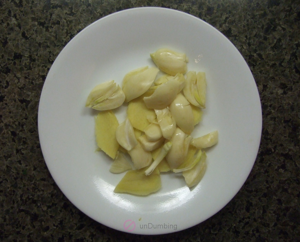 Smashed garlic and sliced ginger on a white plate