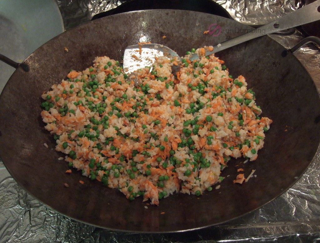 Stir-fried rice, salmon, and peas in a wok