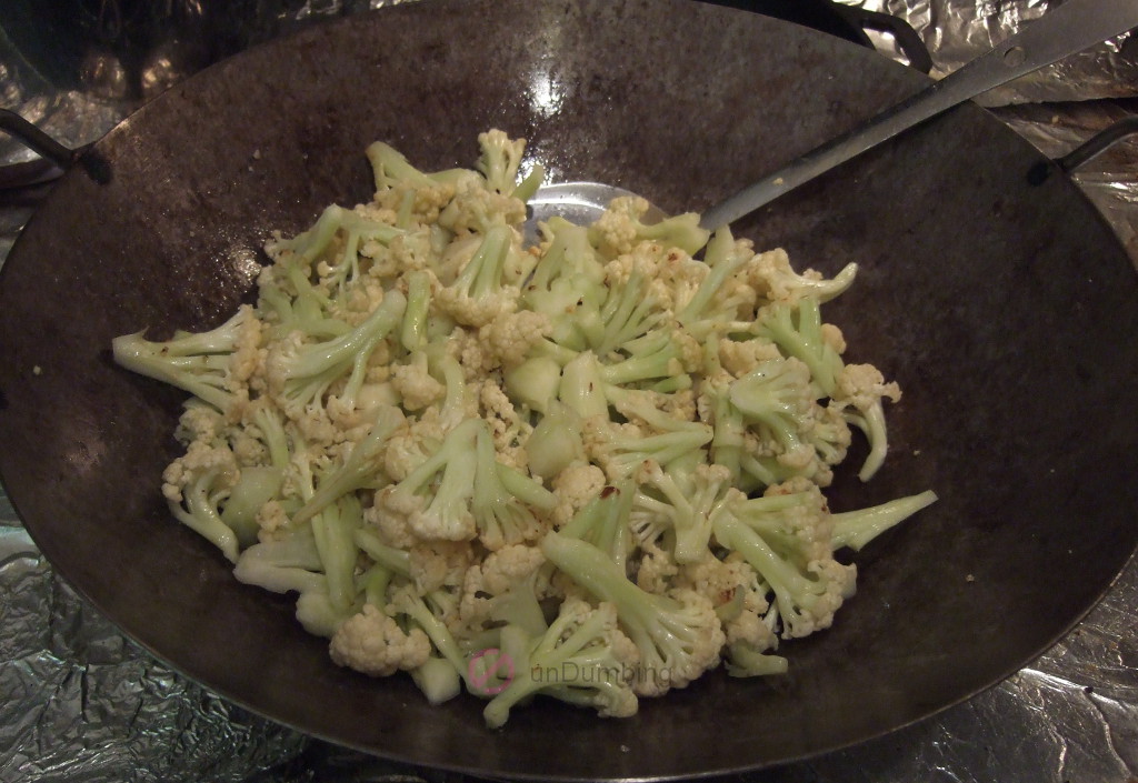 Cauliflower seasoned, stirred, and flipped in the wok
