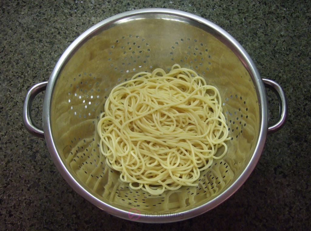 Noodles straining in a stainless steel colander