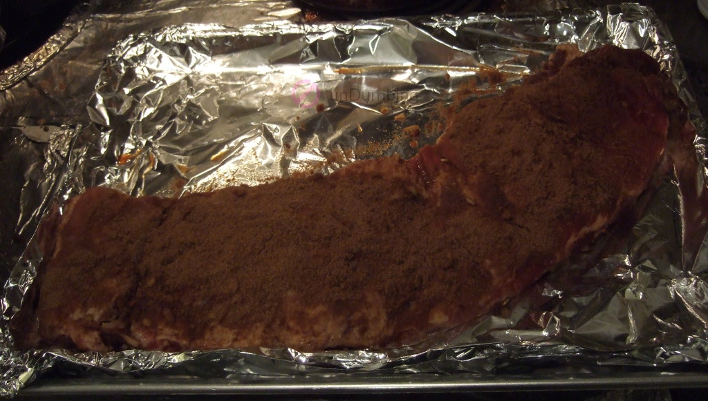 Marinated ribs with cumin on a foil-lined baking sheet