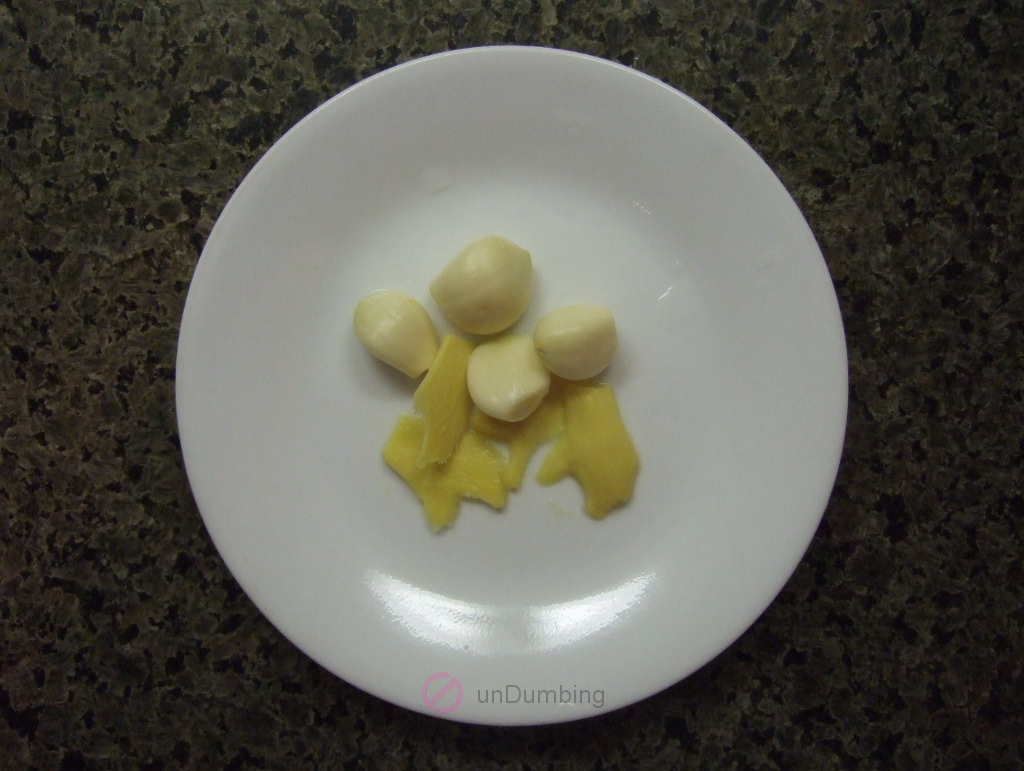 Garlic cloves and ginger slices on a white plate