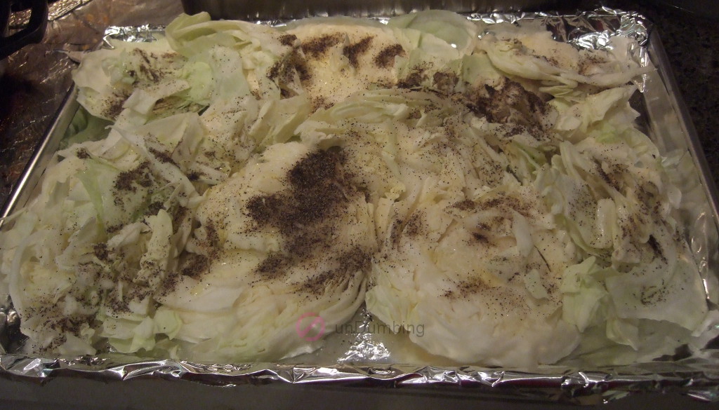 Cabbage slices with seasoning on a foil-lined baking sheet