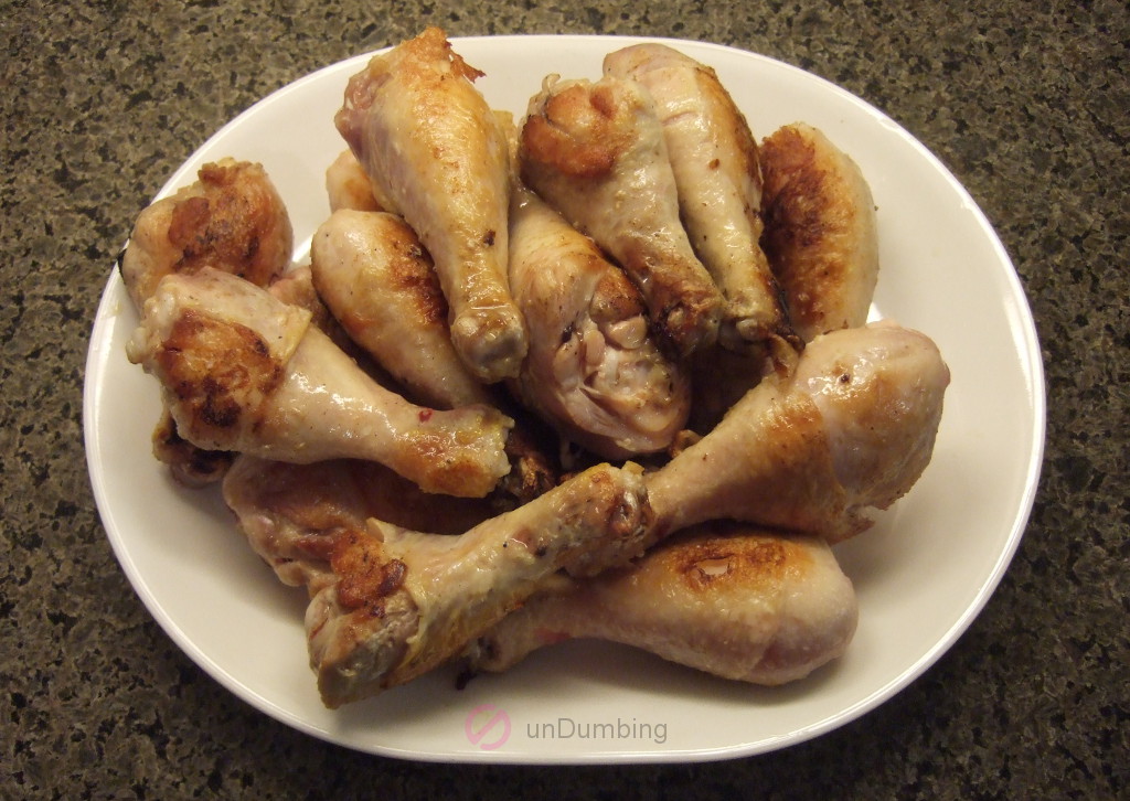Browned chicken drumsticks on a white plate
