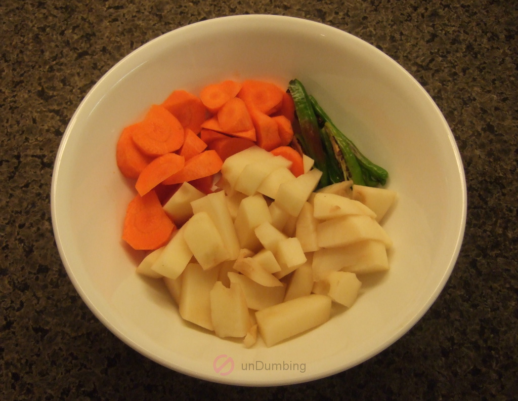 Chopped carrots, green chilies, and potatoes in a white bowl
