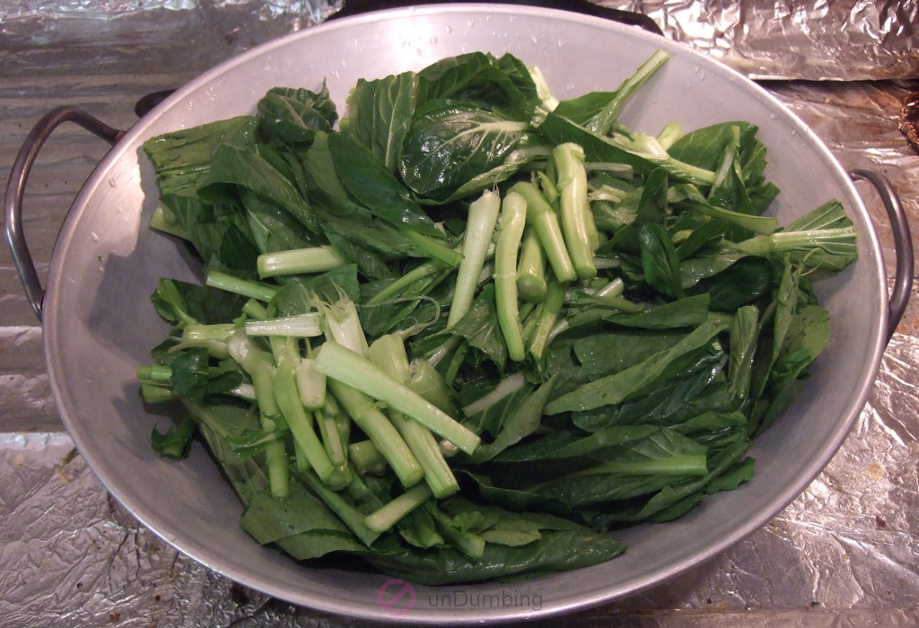 Cut-up Yu Choy in an inverted wok cover on a wok
