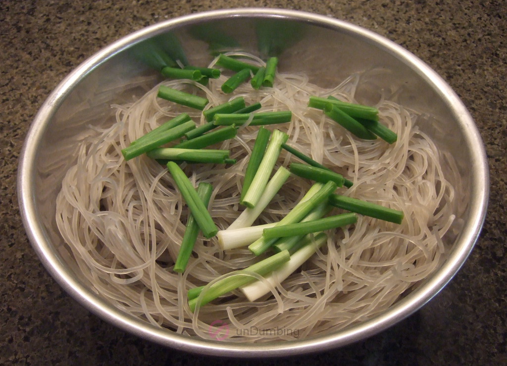 Soaked glass noodle and green onions in a stainless steel bowl