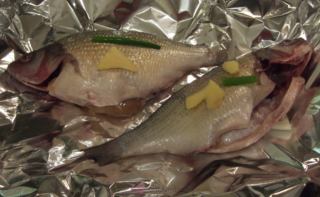 Perch with scallion and ginger on foil-lined roasting pan
