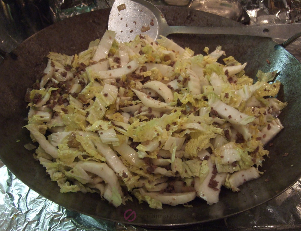Soy sauce, oyster sauce, and cabbage added to the wok and combined