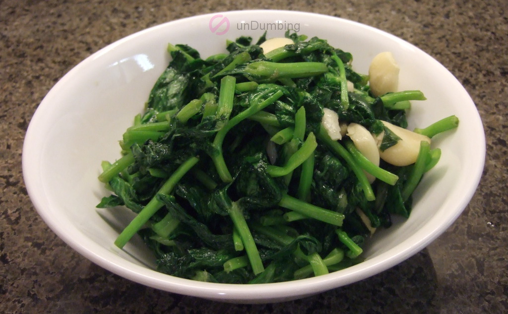 Stir-fried pea shoots with garlic in a white bowl