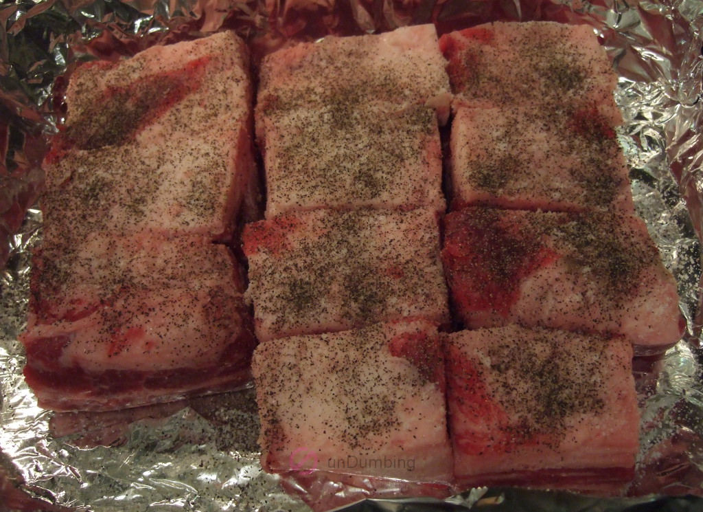 Seasoned ribs on a foil-lined pan