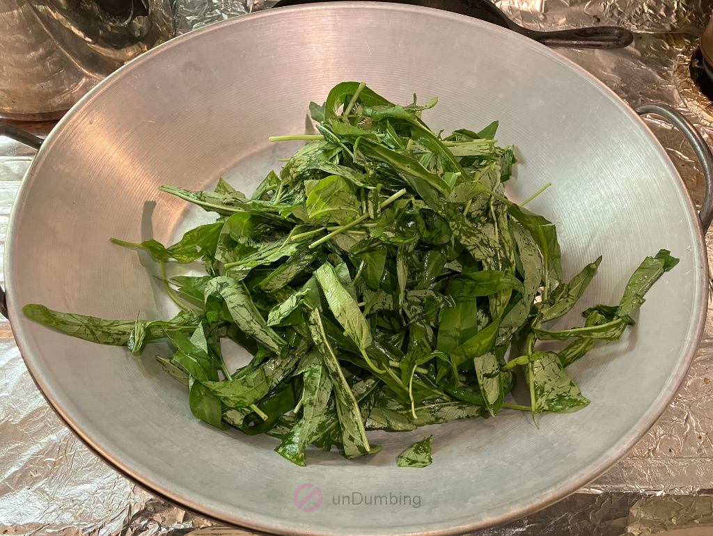 Washed ong choy leaves in a wok cover over the wok