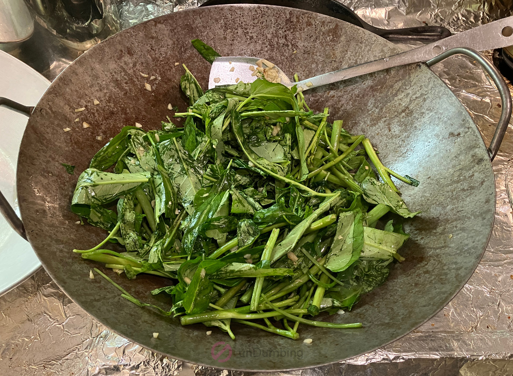 Sautéing ong choy in a wok before seasoning