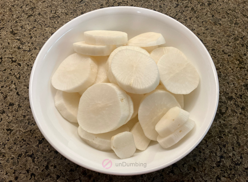 Peeled and sliced daikon in a white bowl