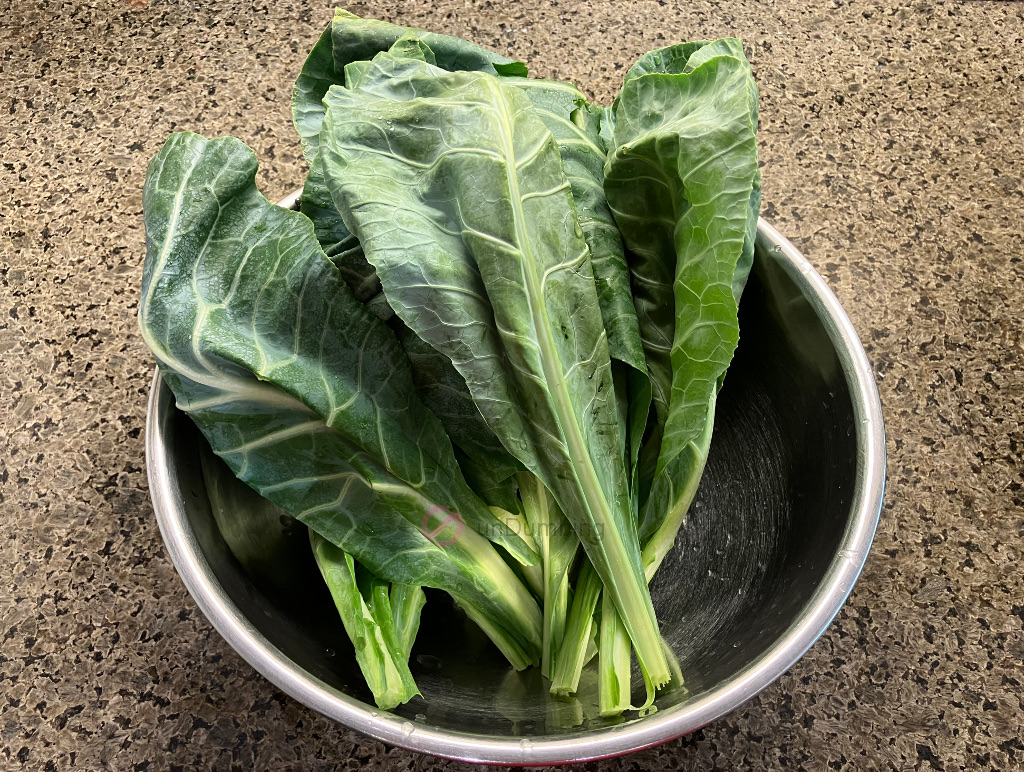 Washed and trimmed collard greens in a stainless steel bowl